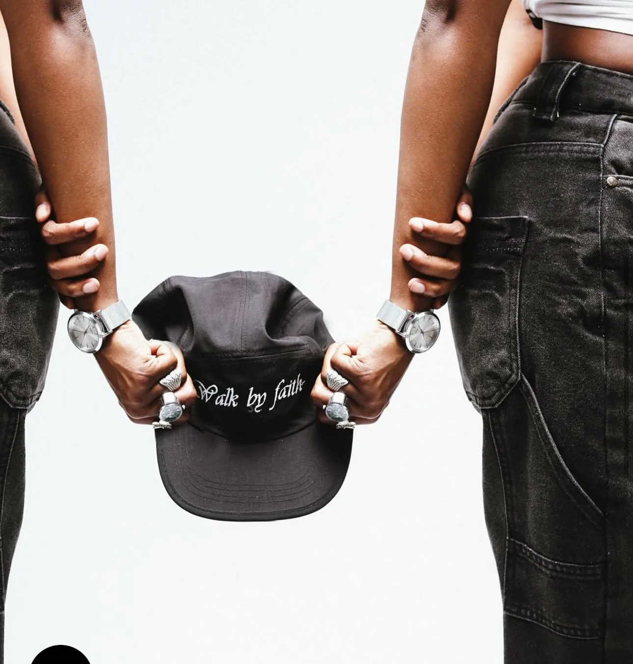 Two people back to back holding the 7nity Walk By Faith cap